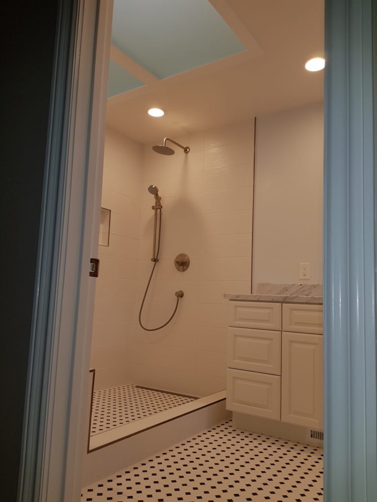 Doorway view of a bathroom with pale pink walls and ceiling and a high shower area