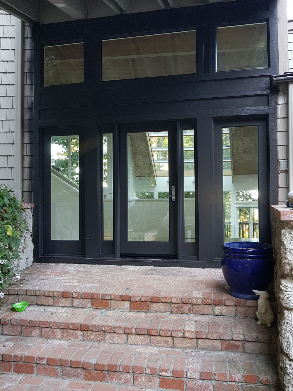 Black-framed glass front door with framed glass panels surrounding it  