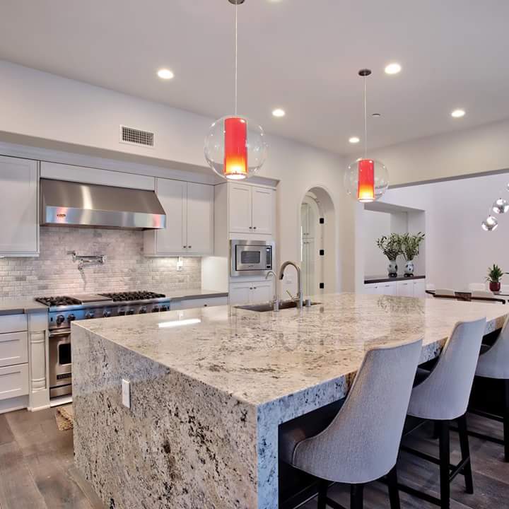 Grey marble center island with high chairs in a pale grey kitchen with pale grey cabinetryGrey marble center island with high chairs in a pale grey kitchen with pale grey cabinetry