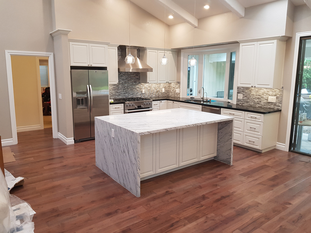 White spotted kitchen center island with cream-colored walls, white cabinetry, and brown backsplashes