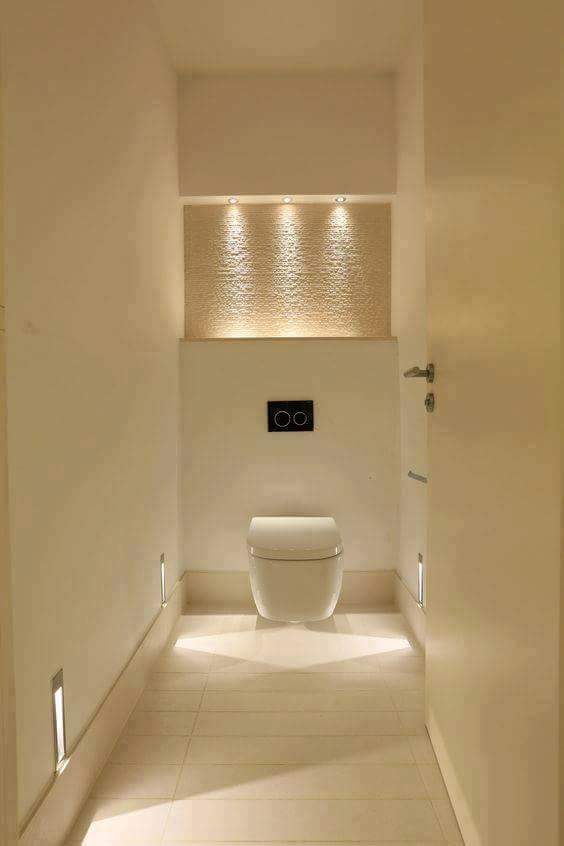 Narrow cream-colored room with a toilet against the furthest wall