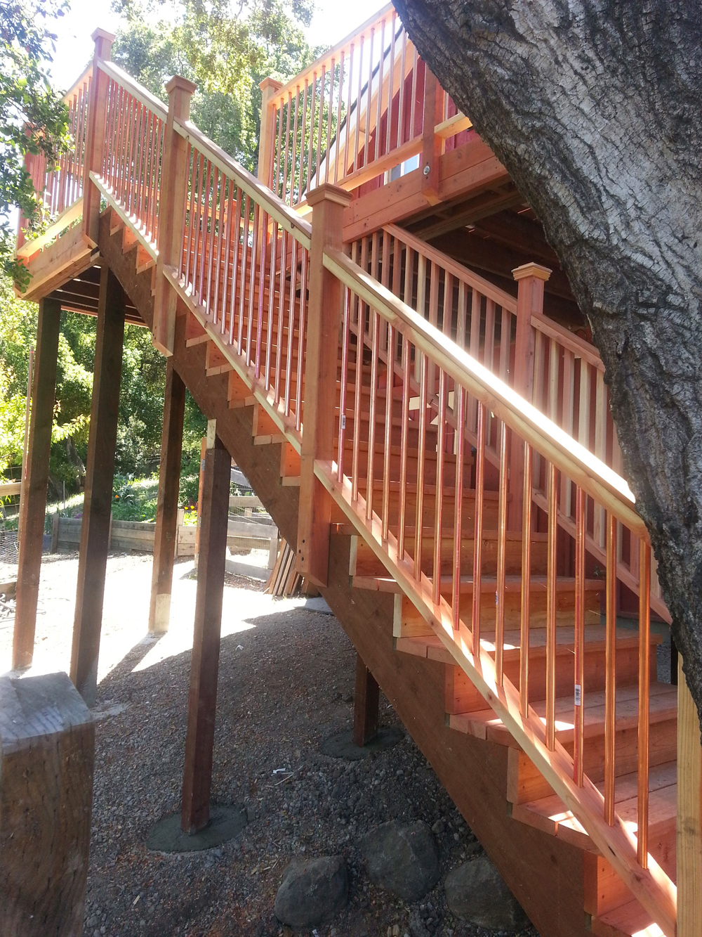 Cedar-brown wooden staircase with light brown wooden railings leading up to an enclosed second-floor deck area