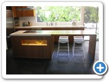 Center kitchen island in front of a wide window and a glass door 